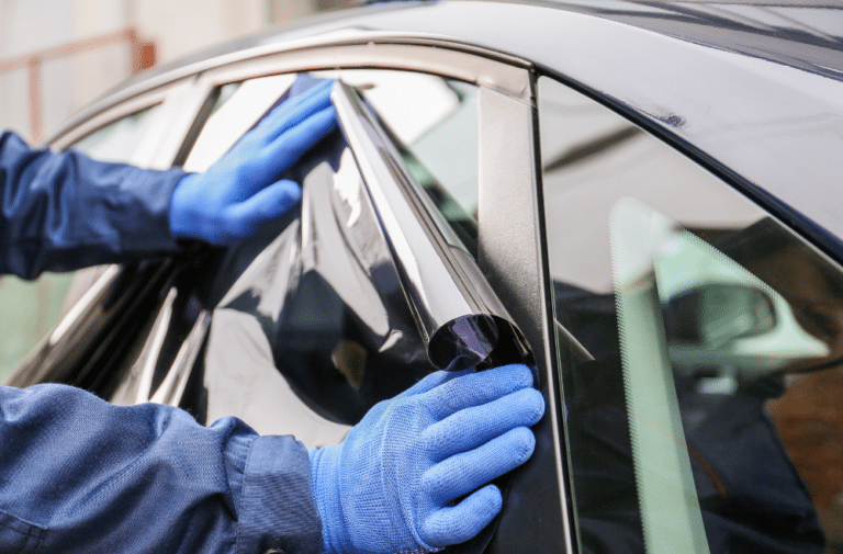 Employee with mobile tinting service applying window tint to car