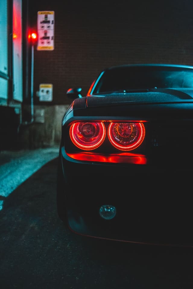 Custom Car Lighting - Picture of a black car at night with red head lights